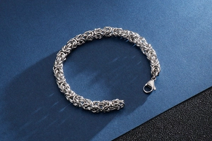 Macro detail of men's interlocking woven stainless steel chain bracelet with lobster clasp