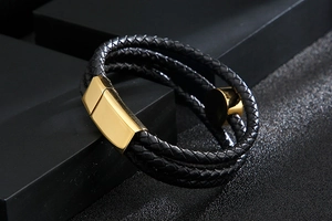 Detail of multi-layer black braided leather bracelet with golden magnetic metal clasp