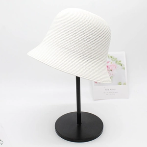 Detailaufnahme eines eleganten weißen Strohhutes auf einem minimalistischen Metallständer