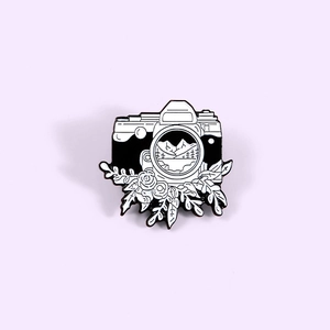 Minimalist black and white camera enamel brooch with landscape and floral details