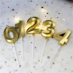 Elegant gold numeral birthday candles 0-4 with metallic finish on white sequined fabric