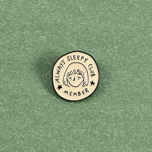 Detailansicht der runden Emaille-Anstecknadel Always Sleepy Club Member mit Cartoon