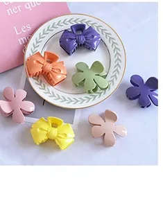 Close-up of colorful matte spring hair clips in floral and bow shapes on a porcelain tray