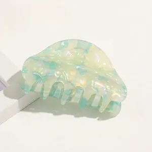Detailed close-up of marble acetate hair claw clip with pearlescent mint green and yellow finish
