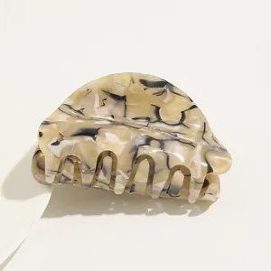 Macro shot of marble patterned acetate hair claw clip with smooth beige and black texture