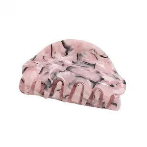 Close-up of a large pink marble acetate hair claw clip with glossy resin finish