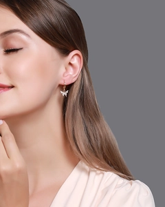 Gros plan d'une boucle d'oreille papillon dorée avec des zircons blancs scintillants