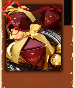 Macro shot of red diamond-shaped candy boxes with gold ribbons and heartfelt engravings