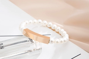 Detailed macro view of white pearls bracelet with a rose gold rectangular metal charm