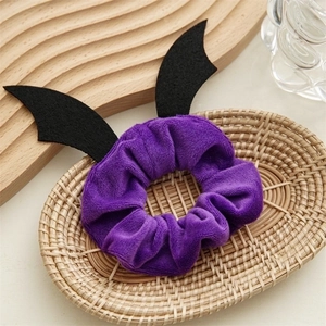 Purple velvet Halloween hair scrunchie with black bat wings in a woven basket