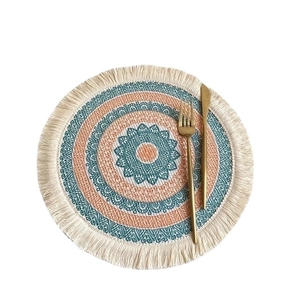 Mandala style woven round placemat with blue and orange fringe tassels on white background