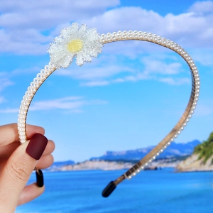 Detail of double-layer faux pearls and a small daisy floral accent on a wedding headband