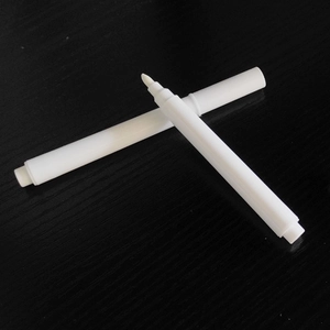 Zwei weiße Flüssigkreide-Marker mit Faserspitzen auf dunklem Holzhintergrund