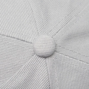 Macro detail of the six-panel crown structure and top button on a light grey baseball cap