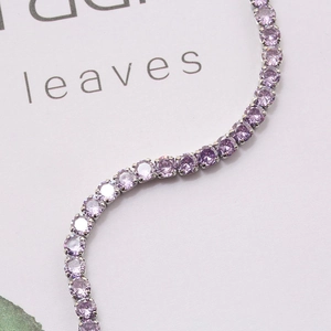 Close-up of a silver tennis bracelet with brilliant purple round-cut cubic zirconia stones
