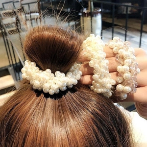 Detail eines hochelastischen Perlenhaargummis für Dutt-Frisuren mit beige-rosa Perlen