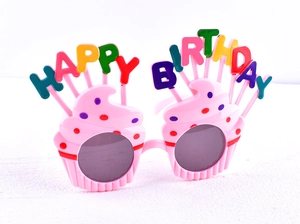 Close-up of pink cupcake birthday glasses with colorful Happy Birthday candle lettering