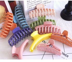 Flat lay of large candy-colored plastic hair claws scattered on a white surface