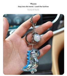 Close-up of iridescent acrylic dinosaur keychain with blue spikes and metallic ring