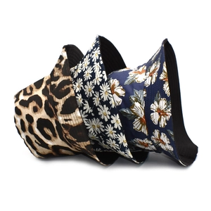 Three bucket hats with leopard, daisy, and tropical floral patterns on white background