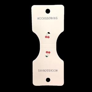 Detailed view of white paper jewelry hang tag with red cherry pattern for accessories