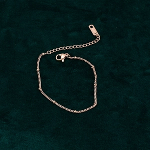 Close-up of 18K gold-plated beaded bracelet with lobster clasp on green velvet