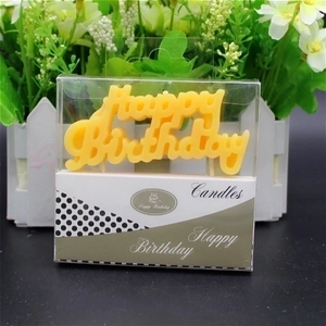 Yellow Happy Birthday letter candle in clear packaging with a floral background