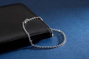 Detail of silver stainless steel cable chain bracelet with lobster clasp on black leather