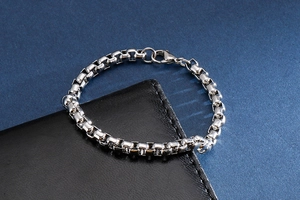 Detail shot of silver box chain bracelet with lobster clasp on premium black leather