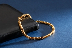 Détail d'un bracelet gourmette en or brillant montrant sa structure à maillons carrés fins