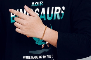 Gros plan d'un bracelet gourmette doré porté au poignet pour un style de mode masculin