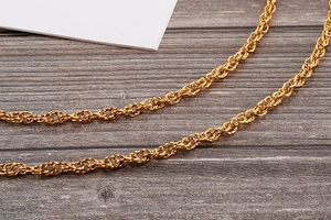 Detailed view of a golden twisted rope chain with metallic luster on wood background