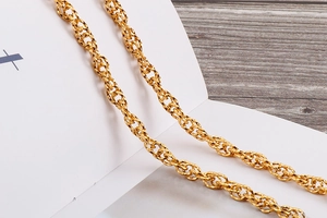 Macro detail of polished gold wavy link chain showing intricate spiral metal craftsmanship