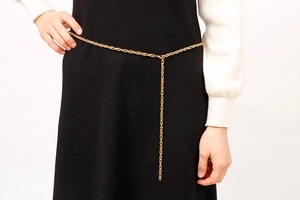 Detail of a gold interlocking ring waist chain on model with a clean white background