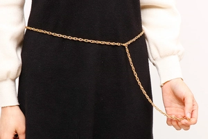 Detail shot of a minimalist gold metal waist chain on a black dress with adjustable clasp