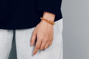 Close-up of golden stainless steel curb chain bracelet worn on wrist for men and women