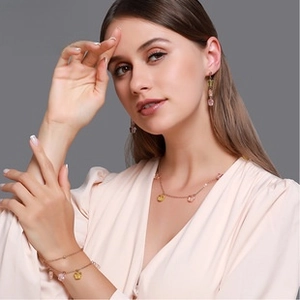 Détail du parure de bijoux MOM dorée avec pendentifs en cristal rose et jaune