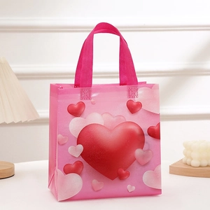 Pink non-woven Valentine's gift bag with red and white heart patterns and sturdy handles