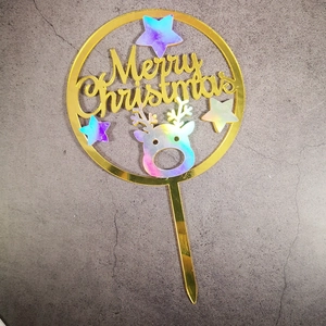 Macro detail of golden acrylic Merry Christmas cake topper with holographic reindeer and stars