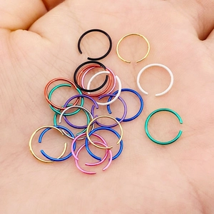 Set of colorful stainless steel C-shaped nose rings shown held in a hand for scale
