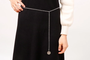 Détail de la chaîne de corps argentée avec pendentif rond sur une robe noire