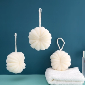 Three large beige mesh bath loofahs with hanging ropes against a deep blue background