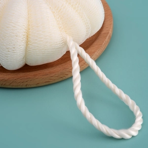 Large white nylon mesh bath ball with woven lanyard on a wooden tray for rich foaming
