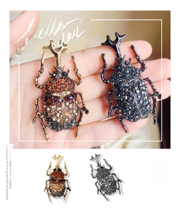 Detailed macro view of rhinestone insect brooches in gold and gunblack finishes