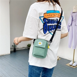 Detailed close-up of mint green canvas crossbody bag featuring daisy floral embroidery