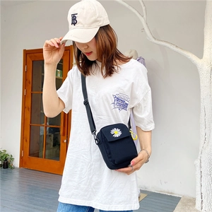 Detail of black canvas crossbody bag with white daisy embroidery on female model