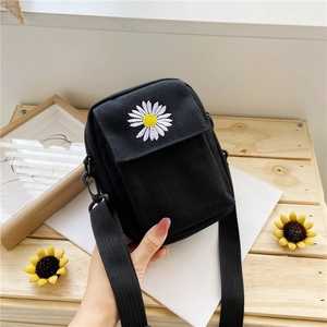 Close-up of black canvas bag featuring white daisy embroidery and woven fabric texture