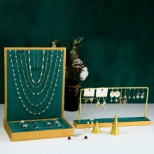 Detail of dark green velvet jewelry box and golden metal earring stand with dried flowers