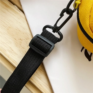 Detail of adjustable black nylon strap with plastic buckle on yellow canvas bag