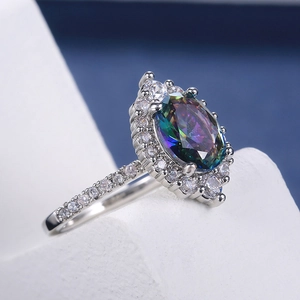 Detailed macro view of an oval mystic topaz ring with four-prong setting and pavé crystals